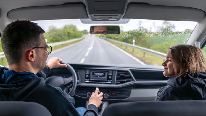 Smiling passenger. Rainy road trip. Front seat in car.