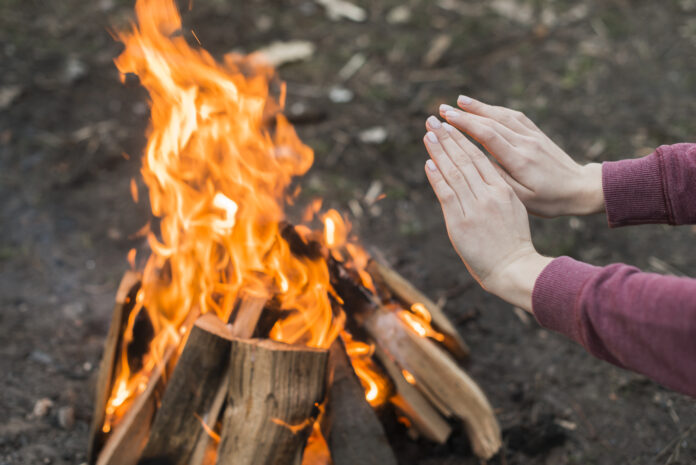 high-angle-woman-warming-bonfire